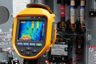 Thermal imager being used to detect hot spots in an electrical panel during safety inspection.